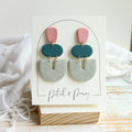 Petal & Posy Otherside earrings in fog, dusky teal, and rose featuring dangling stud design on white background.