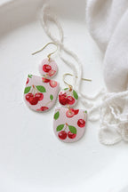Petal & Posy Cherry Bomb Polymer Clay Earrings featuring vibrant red cherry designs on gold hooks.