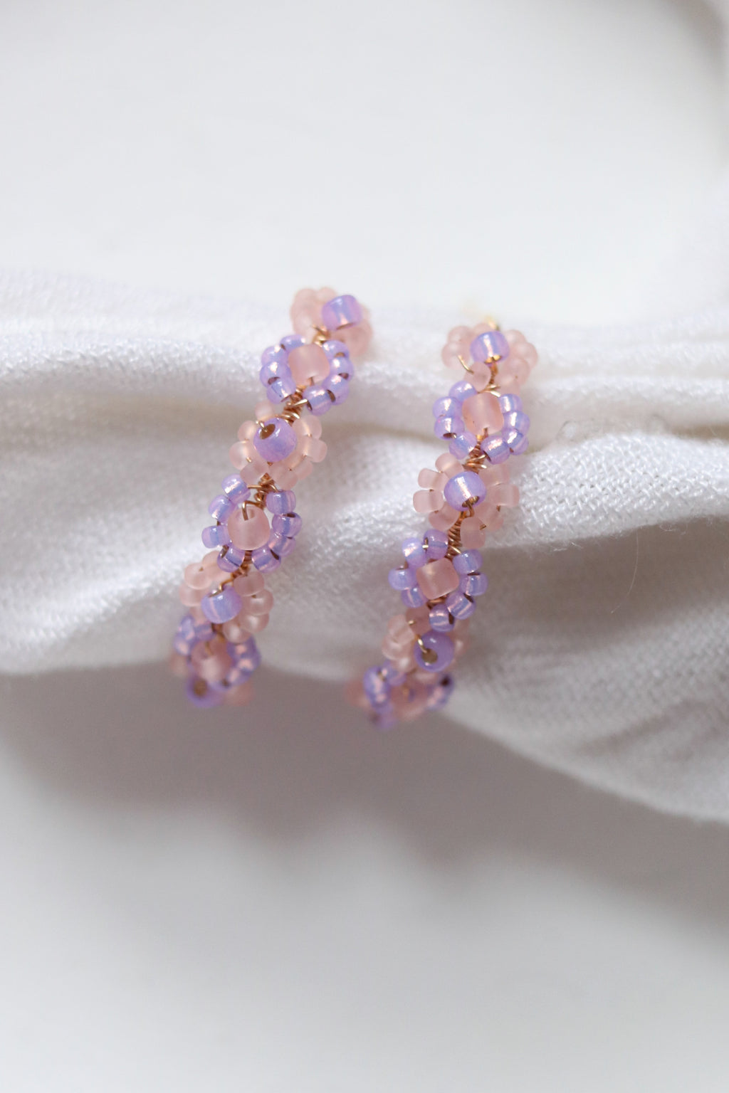 Lilac beaded hoop earrings with daisy chain design from Petal & Posy, featuring intricate hand-beaded details and gold-tone hoops.