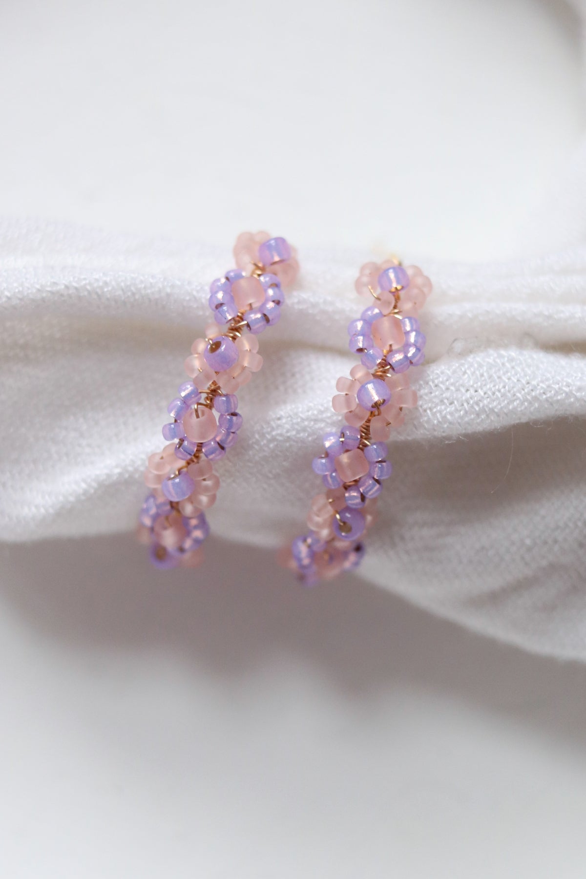 Lilac beaded hoop earrings with daisy chain design from Petal & Posy, featuring intricate hand-beaded details and gold-tone hoops.